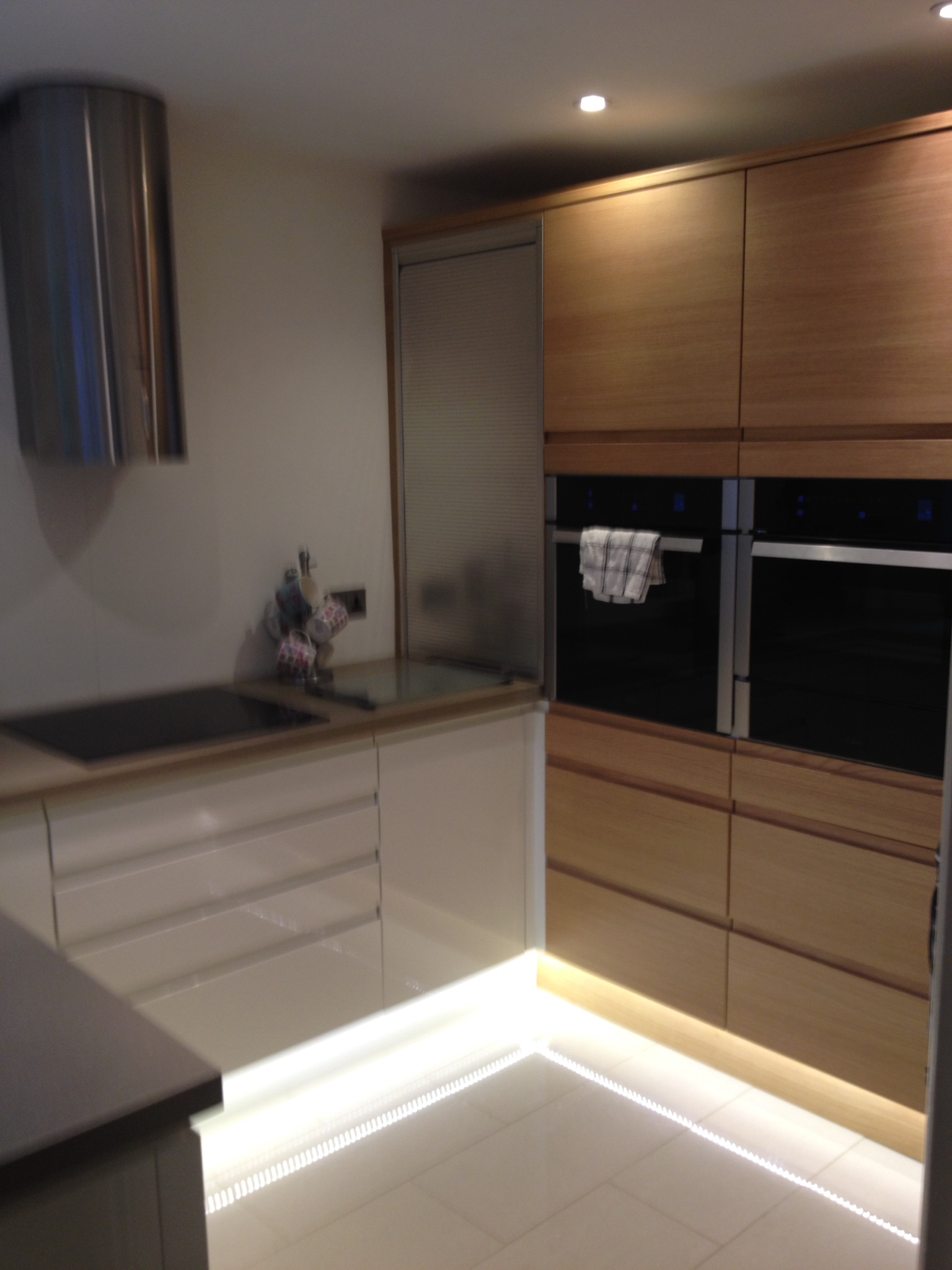 Handleless kitchen in oak and cream gloss with lighting under the plinth
