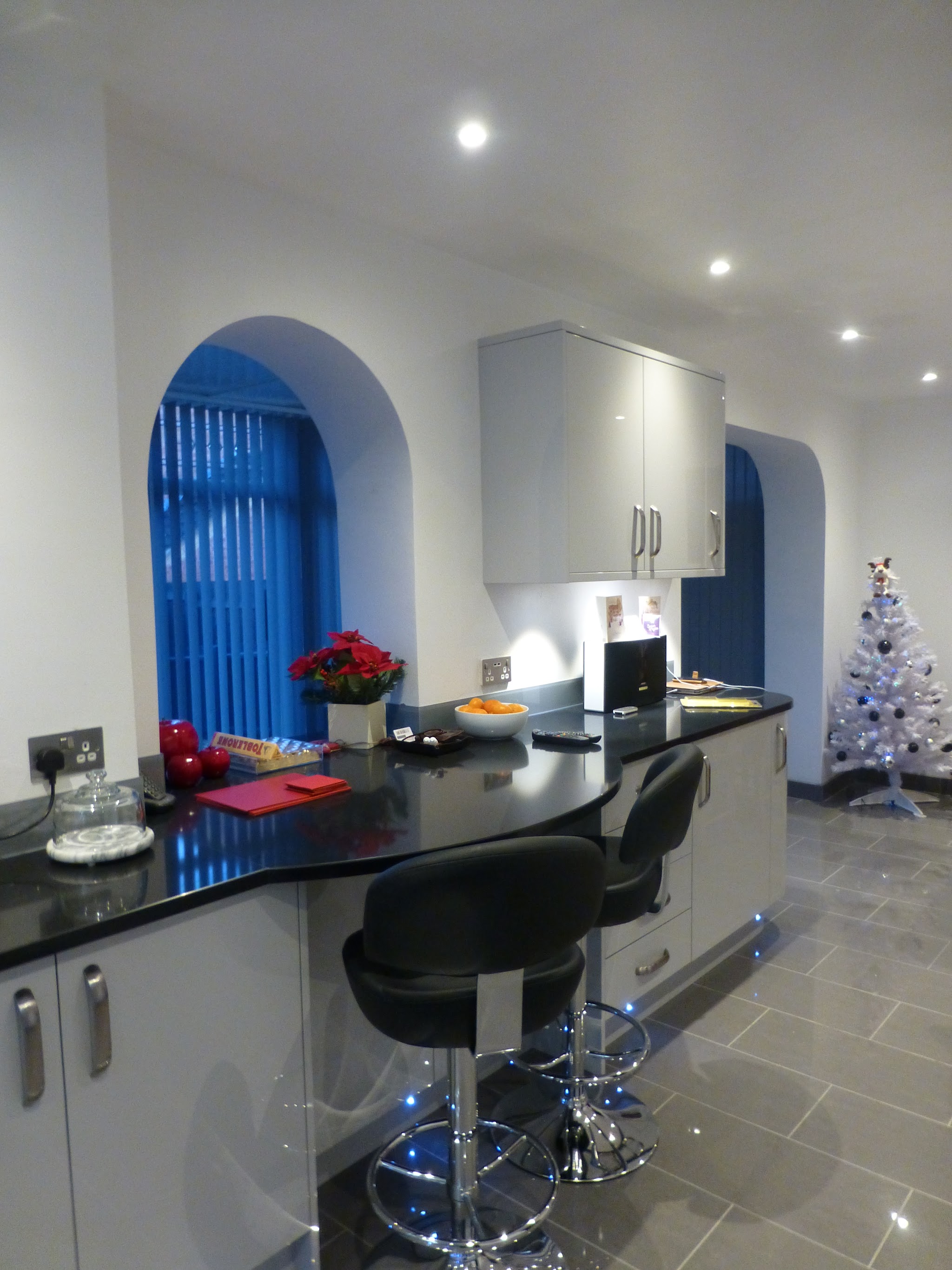 Curved breakfast bar with black worktop and bar stools beside arched alcoves