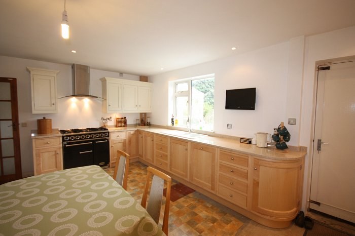 Hand-made natural wood kitchen with a curved end cabinet and range cooker