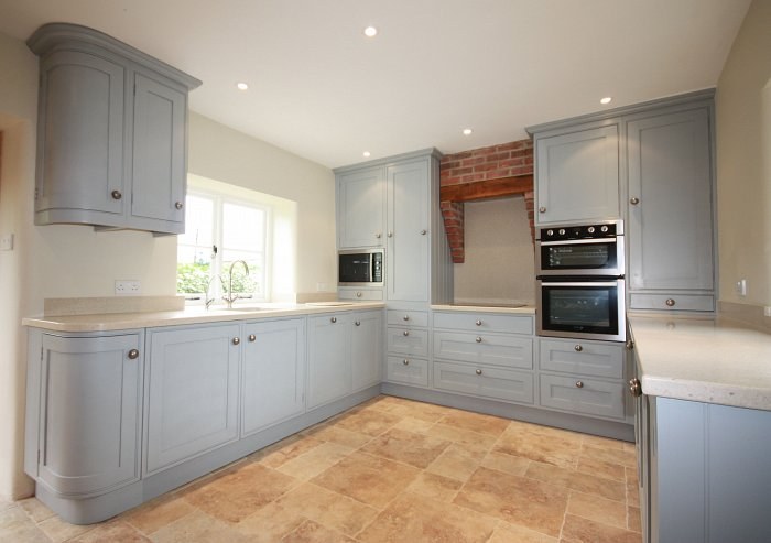Hand-made L-shaped painted kitchen with a brick chimney breast