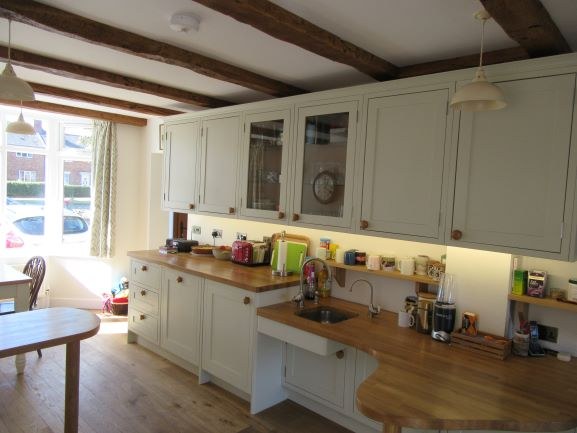 Wheelchair accessible kitchen with lowered oak worktops and open space beneath, under beamed ceilings