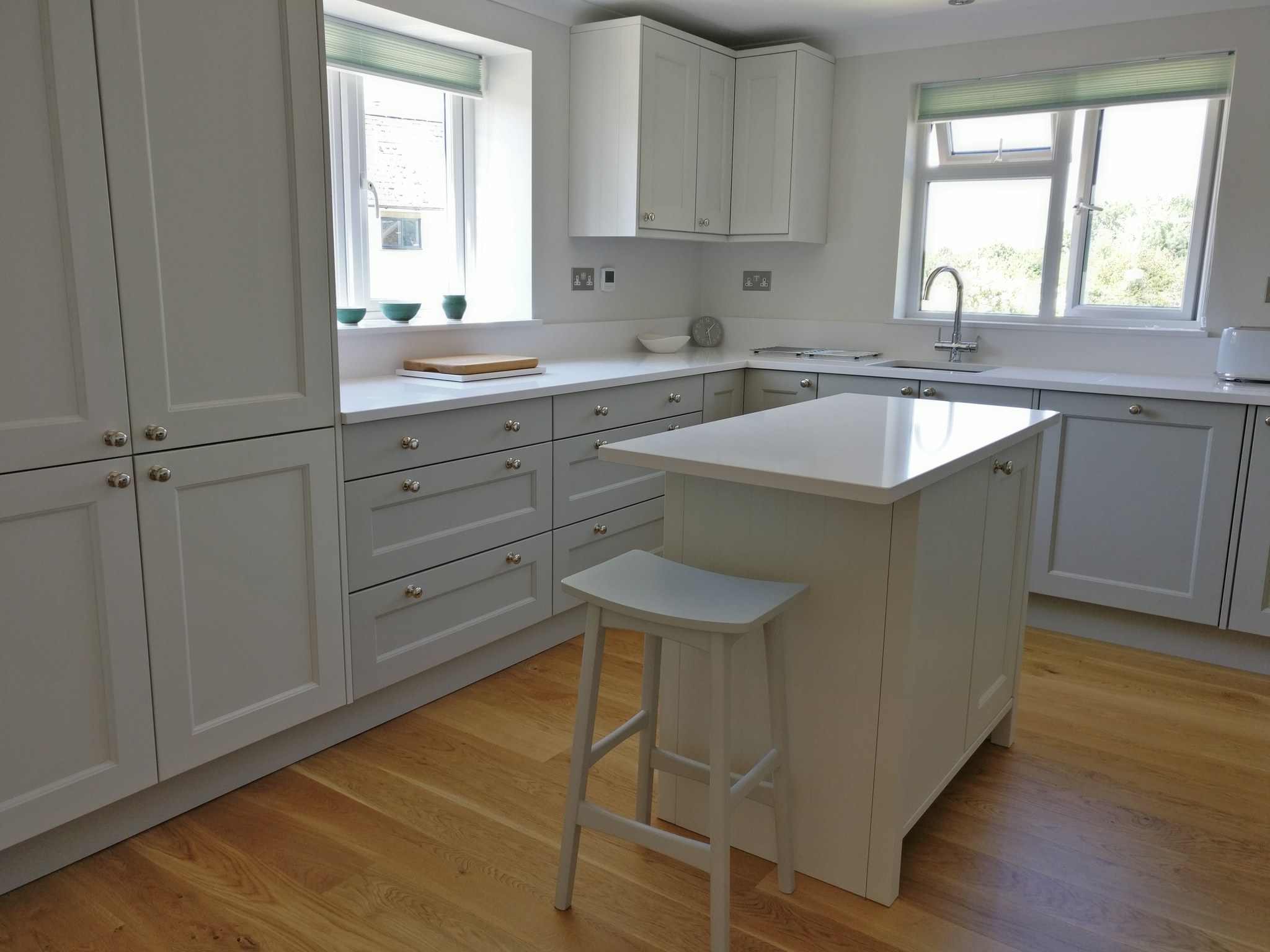 Light grey shaker kitchen with a small island and white quartz worktops in Croughton