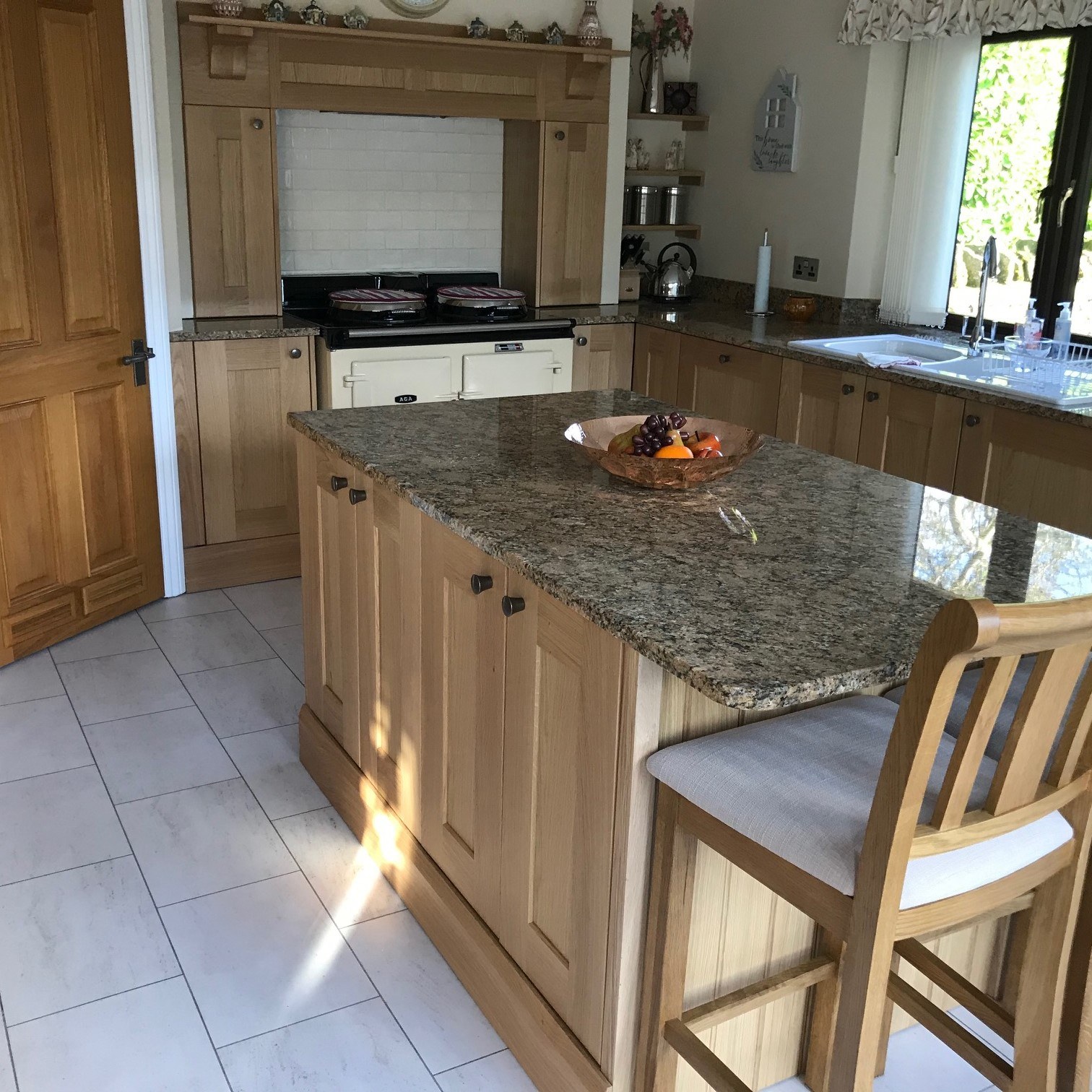 Natural oak kitchen with a granite topped island and seating in Farthinghoe