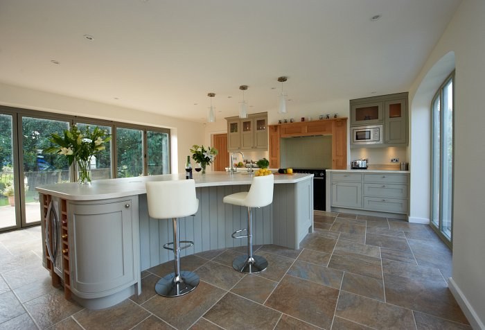 Large curved island with white bar stools in an open plan barn-style kitchen in Kings Sutton