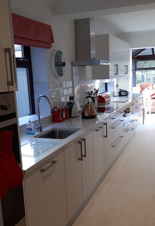 Galley style painted kitchen with a red roman blind in Middleton Cheney