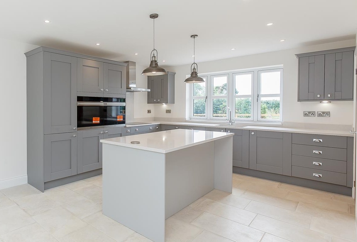 Grey shaker kitchen with a central island and quartz worktops in a new build stone house