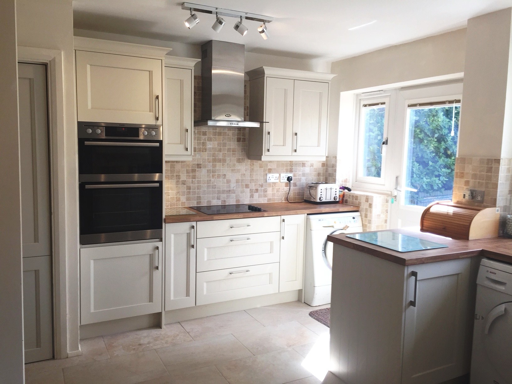 Painted kitchen with a small peninsula and oak worktops in Sibford Ferris